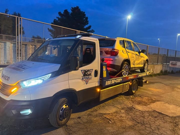 Carro attrezzi Spinelli con un SUV sul pianale, di sera