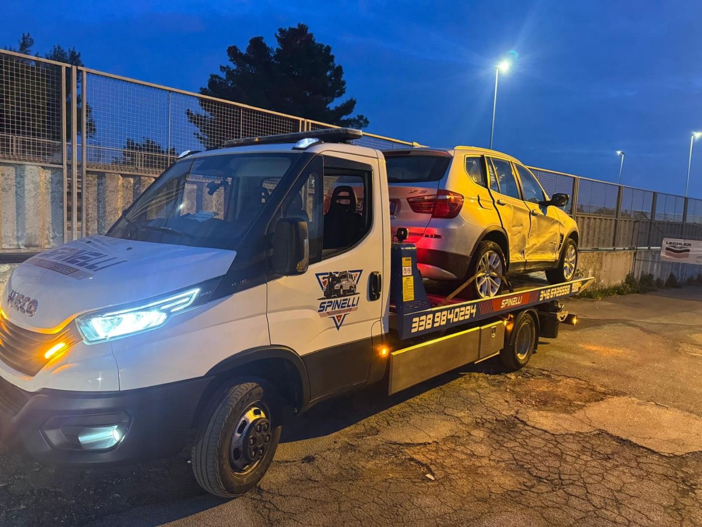 Carro attrezzi Spinelli con un SUV sul pianale, di sera